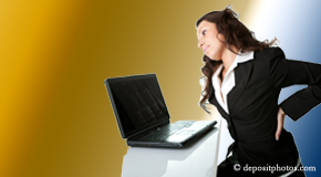 a person Plainville bending over a computer holding her back due to pain